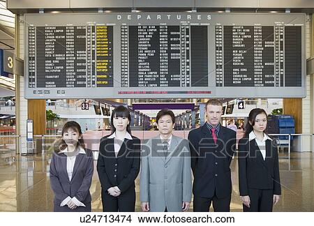 Picture - Portrait of five business executives standing in front of an arrival departure board at an airport. Fotosearch