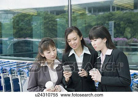 Three businesswomen looking at a personal data assistant at an airport lounge View Large Photo Image Stock Photography - Three businesswomen looking at a personal data assistant at an airport lounge. Fotosearch