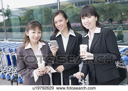 Stock Photo - Three businesswomen waiting at an airport lounge. Fotosearch