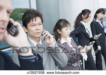 Stock Photo - Three businesswomen with two businessmen waiting at an airport lounge. Fotosearch