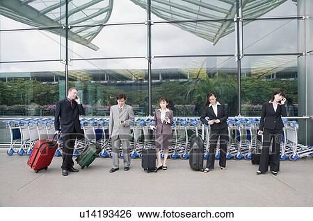 Stock Photograph - Three businesswomen with two businessmen waiting at an airport lounge. Fotosearch