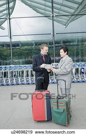 Two businessmen discussing a document outside an airport View Large Photo Image Stock Photo - Two businessmen discussing a document outside an airport. Fotosearch