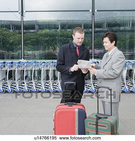 Stock Photography - Two businessmen discussing a document outside an airport. Fotosearch