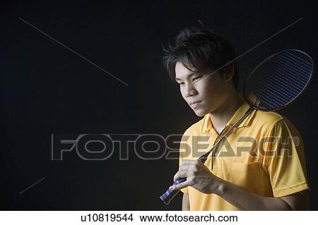 Picture - Close-up of a young man holding a badminton racket. Fotosearch