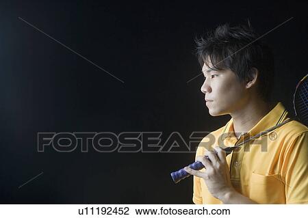 Stock Image - Close-up of a young man holding a badminton racket. Fotosearch