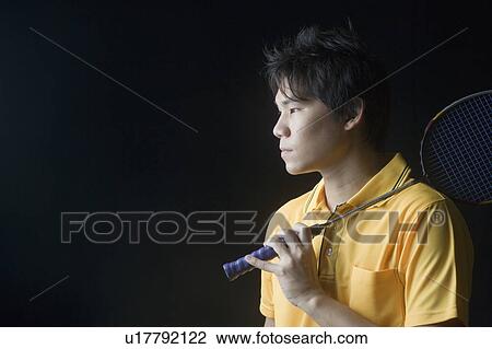 Stock Image - Close-up of a young man holding a badminton racket. Fotosearch