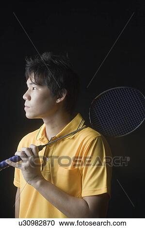 Stock Image - Close-up of a young man holding a badminton racket. Fotosearch