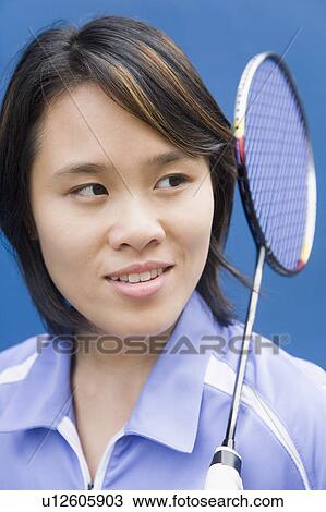 Stock Image - Close-up of a young woman with a badminton racket and smiling. Fotosearch