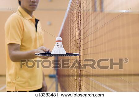 Mid section view of a young man standing in a badminton court and holding a badminton racket View Large Photo Image Stock Image - Mid section view of a young man standing in a badminton court and holding a badminton racket. Fotosearch
