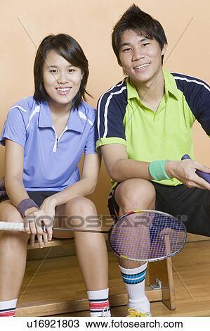 Portrait of a young couple sitting on a bench and holding badminton rackets View Large Photo Image Stock Image - Portrait of a young couple sitting on a bench and holding badminton rackets. Fotosearch