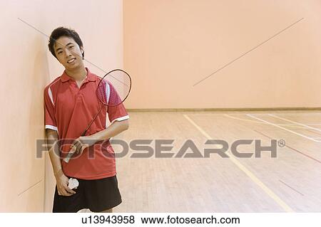 Stock Photo - Portrait of a young man holding a badminton racket and a shuttlecock. Fotosearch