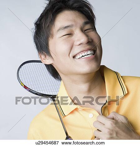 Stock Photo - Portrait of a young man smiling with a badminton racket. Fotosearch
