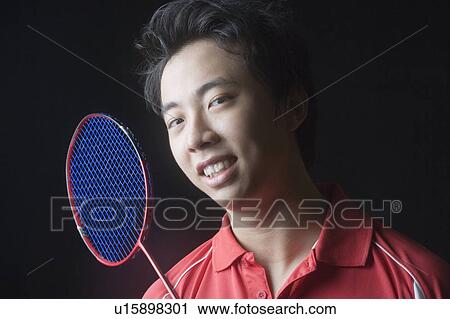 Stock Image - Portrait of a young man with a badminton racket. Fotosearch