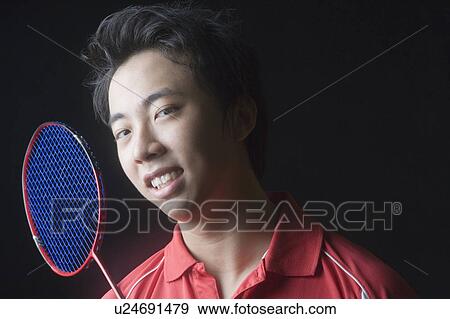 Stock Photo - Portrait of a young man with a badminton racket. Fotosearch