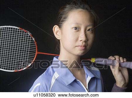 Stock Image - Portrait of a young woman holding a badminton racket. Fotosearch