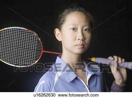 Stock Image - Portrait of a young woman holding a badminton racket. Fotosearch