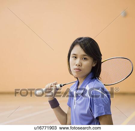 Stock Image - Portrait of a young woman holding a badminton racket. Fotosearch
