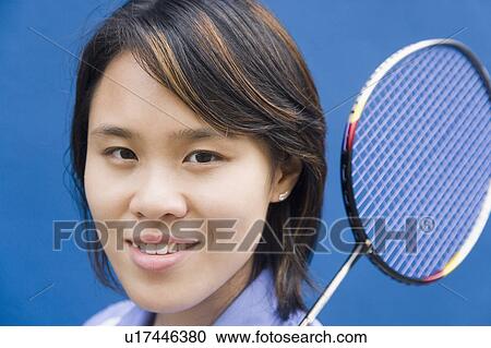 Stock Image - Portrait of a young woman holding a badminton racket. Fotosearch