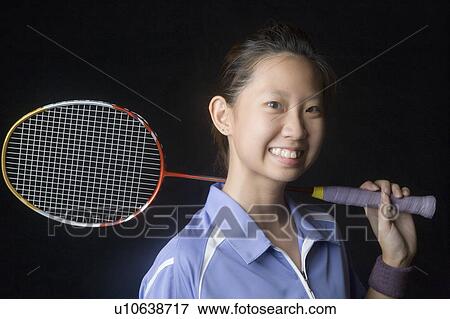 Portrait of a young woman holding a badminton racket and smiling View Large Photo Image Stock Photo - Portrait of a young woman holding a badminton racket and smiling. Fotosearch