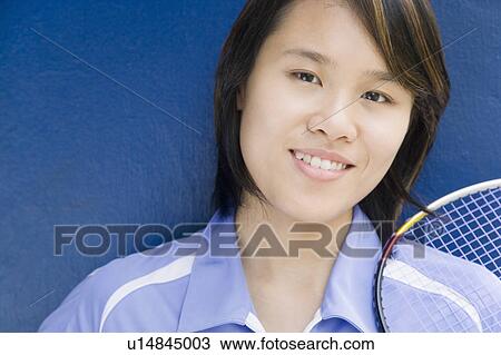 Stock Image - Portrait of a young woman with a badminton racket and smiling. Fotosearch