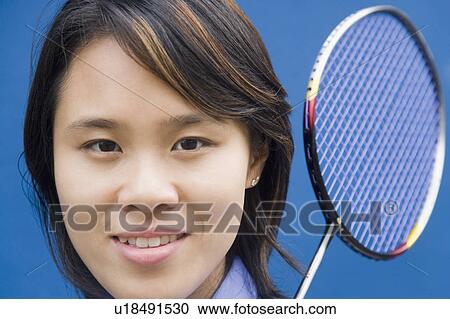 Stock Image - Portrait of a young woman with a badminton racket and smiling. Fotosearch