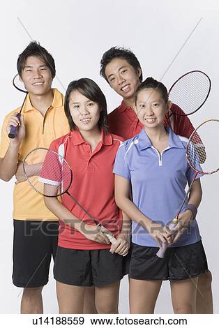 Stock Photo - Portrait of two young couples holding badminton rackets and smiling. Fotosearch