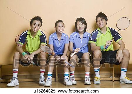 Portrait of two young women and two young men sitting side by side on a bench and holding badminton rackets View Large Photo Image Stock Photography - Portrait of two young women and two young men sitting side by side on a bench and holding badminton rackets. Fotosearch