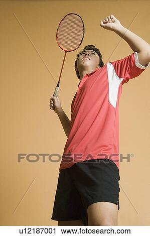 Stock Image - Side profile of a young man playing badminton. Fotosearch