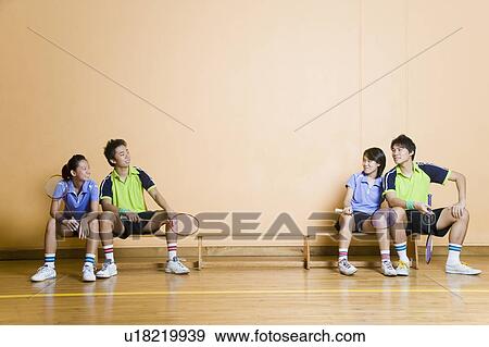 Two young couples sitting on a bench and holding badminton rackets View Large Photo Image Stock Photo - Two young couples sitting on a bench and holding badminton rackets. Fotosearch