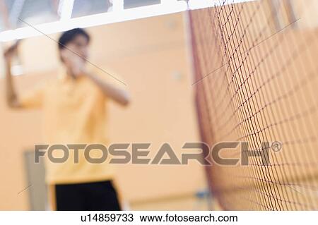 Stock Image - Young man playing in a badminton court. Fotosearch