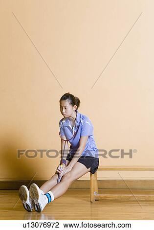 Young woman sitting on a bench and holding a badminton racket View Large Photo Image Stock Image - Young woman sitting on a bench and holding a badminton racket. Fotosearch