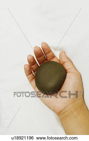 Stock Photograph - Close-up of a person's hand holding a spa hot stone. Fotosearch