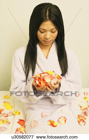Stock Photo - Close-up of a young woman holding a hand full of petals. Fotosearch