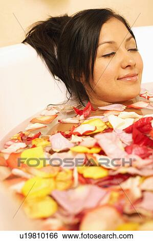 Close-up of a young woman relaxing in a bathtub filled with flower petals View Large Photo Image Stock Photograph - Close-up of a young woman relaxing in a bathtub filled with flower petals. Fotosearch