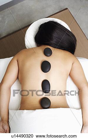 Stock Image - High angle view of a woman getting hot stone therapy. Fotosearch