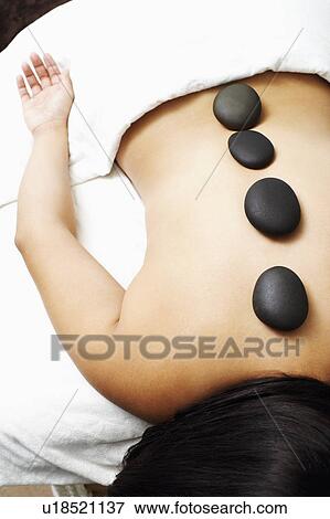 Stock Photo - High angle view of a woman getting hot stone therapy. Fotosearch