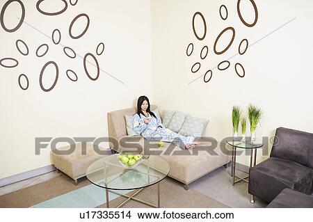 Picture - High angle view of a young woman reclining on a couch. Fotosearch