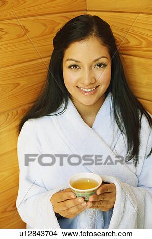 Picture - Portrait of a young woman holding a cup of aromatherapy oil and smiling. Fotosearch