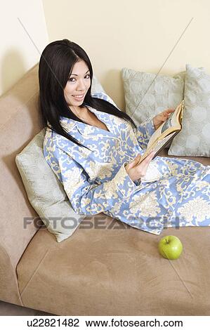 Stock Image - Portrait of a young woman holding a book and smiling. Fotosearch
