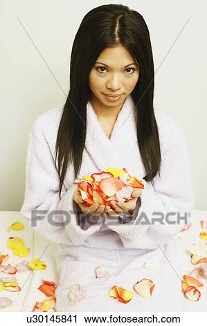 Stock Image - Portrait of a young woman holding a hand full of petals. Fotosearch