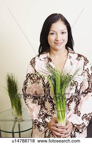Stock Photo - Portrait of a young woman holding a houseplant. Fotosearch