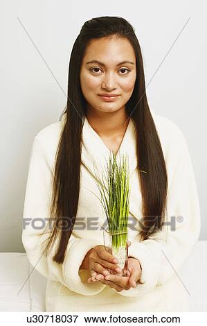 Stock Photo - Portrait of a young woman holding wheatgrass and smiling. Fotosearch