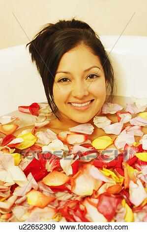 Stock Photo - Portrait of a young woman in a bathtub filled with flower petals. Fotosearch