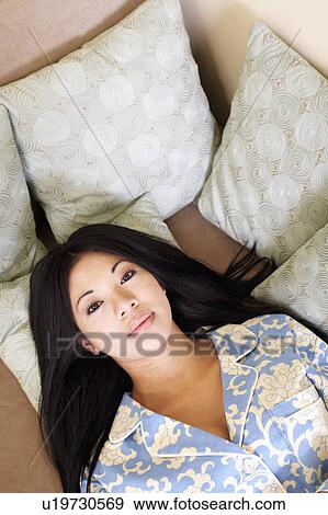 Stock Photo - Portrait of a young woman lying on a couch. Fotosearch