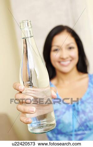 Stock Image - Portrait of a young woman showing a water bottle. Fotosearch
