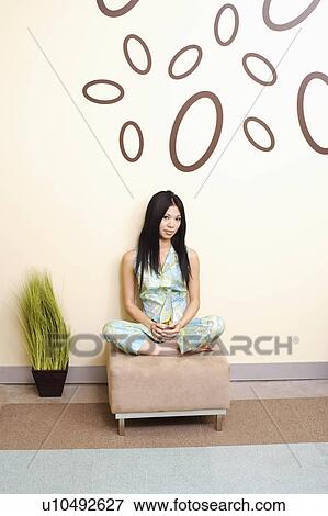 Portrait of a young woman sitting and holding a bottle View Large Photo Image Stock Photo - Portrait of a young woman sitting and holding a bottle. Fotosearch