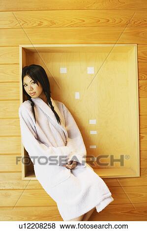 Stock Photo - Portrait of a young woman sitting in a box on the wall. Fotosearch
