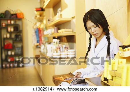 Stock Photo - Side profile of a young woman reading a magazine. Fotosearch