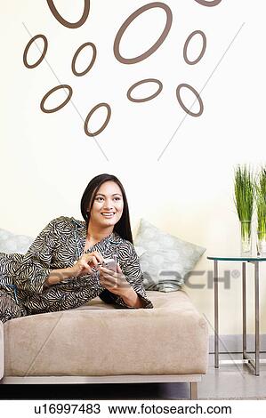 Young woman using a hand held device and smiling View Large Photo Image Stock Image - Young woman using a hand held device and smiling. Fotosearch