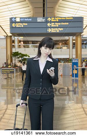 Businesswoman leaving an airport and looking at a mobile phone View Large Photo Image Stock Image - Businesswoman leaving an airport and looking at a mobile phone. Fotosearch